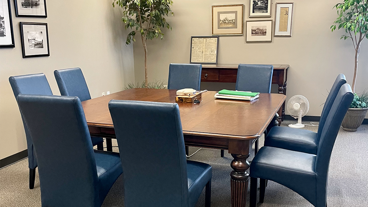 A table with blue chairs and a picture on the wall.